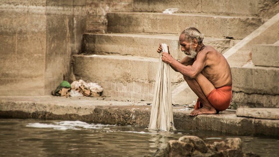 Man washing cloth on the stone steps of a ghat in Varanasi