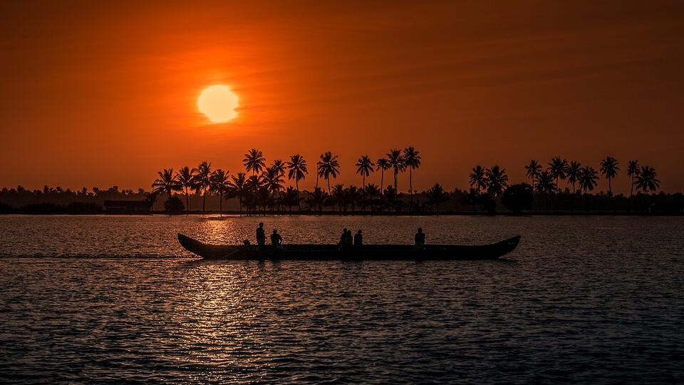 Fishermen in a canoe at sunset on the backwaters of Kerala