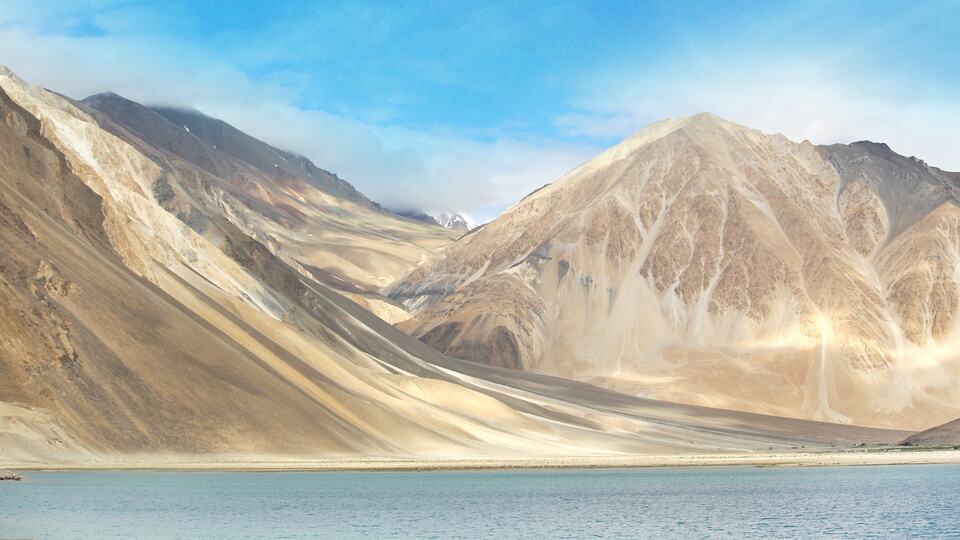 Barren mountains rising above a turquoise lake in Ladakh