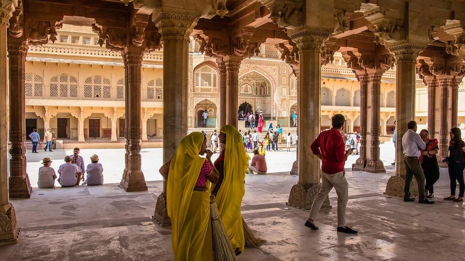 Women in saris walking through a pillared hall of Amber Fort