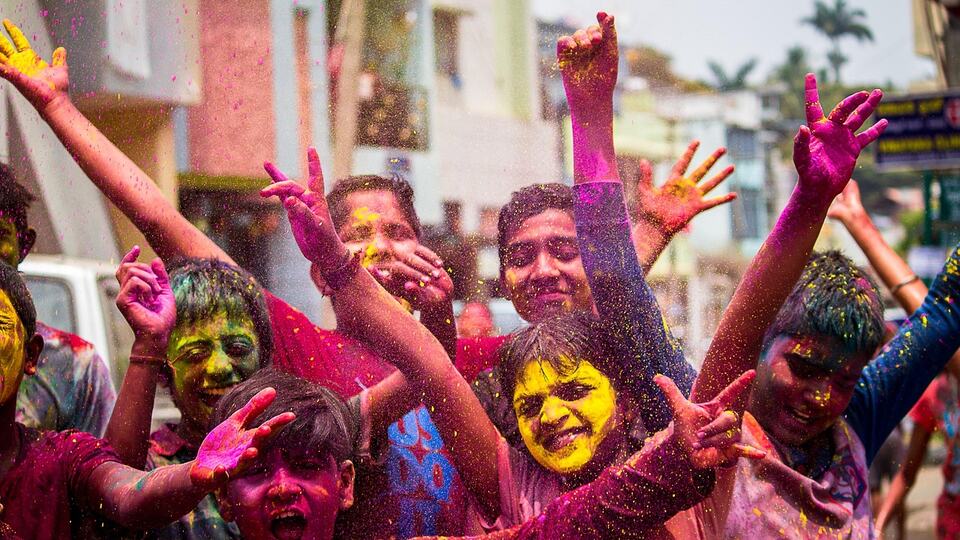 Young people covered in bright colours celebrating the Holi festival