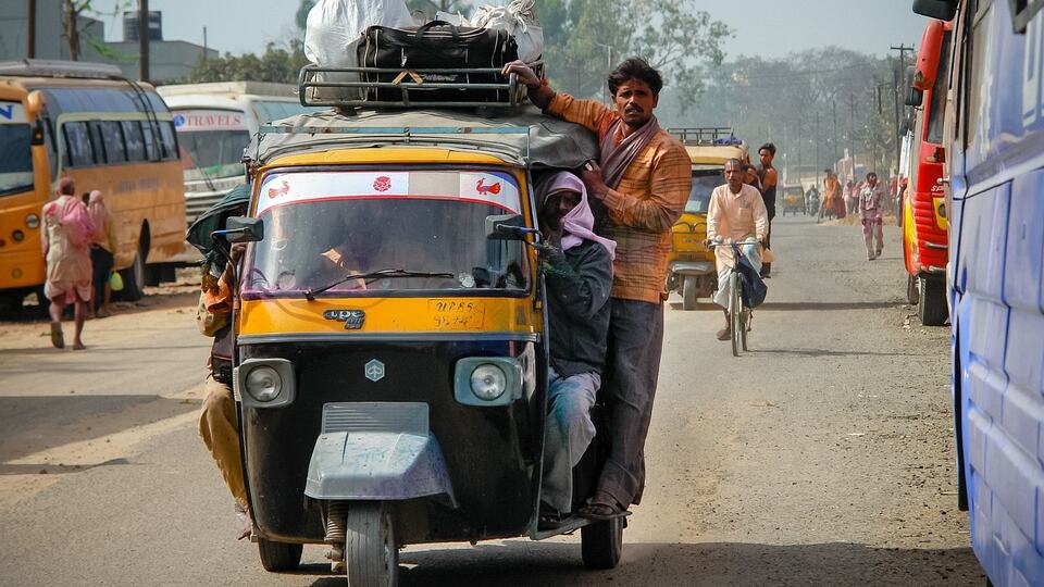 Auto-rickshaw taxi driving through a busy street in an Indian city
