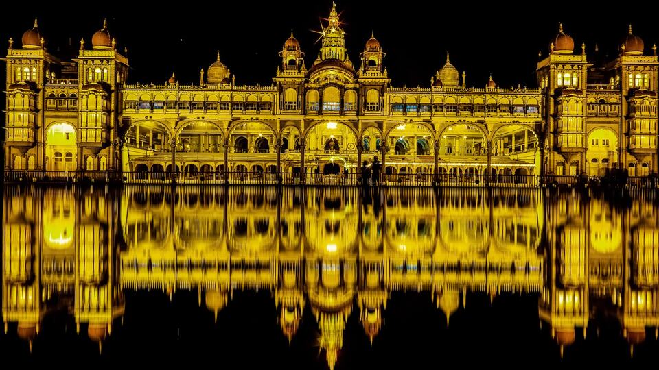 Mysore Palace illuminated at night and reflected in water