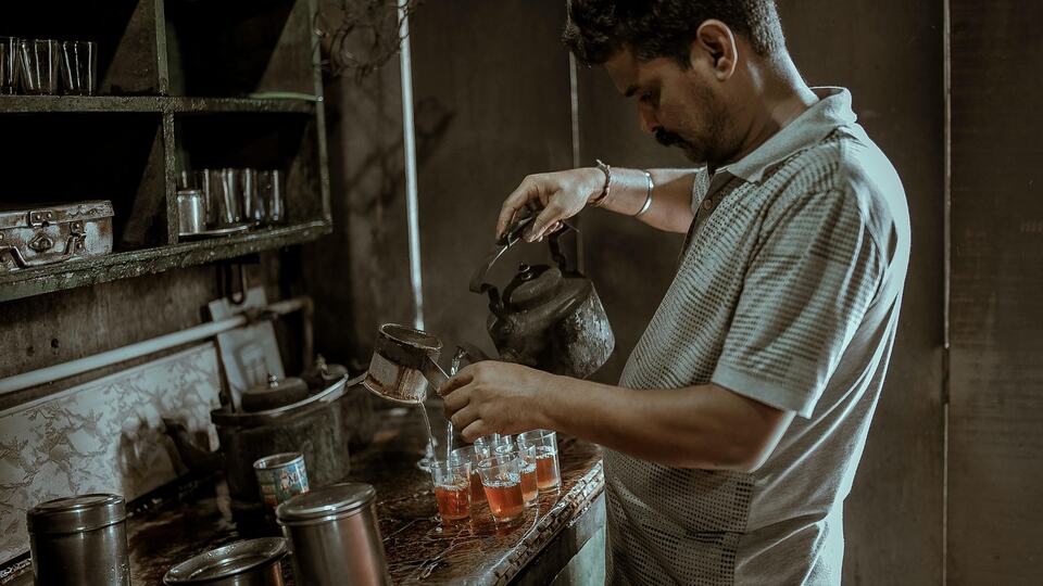 Chai wallah pouring tea at a traditional Indian tea stall