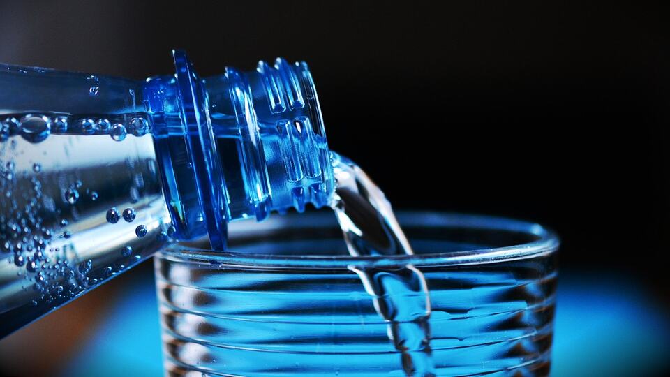 Clean drinking water being poured from a bottle into a glass