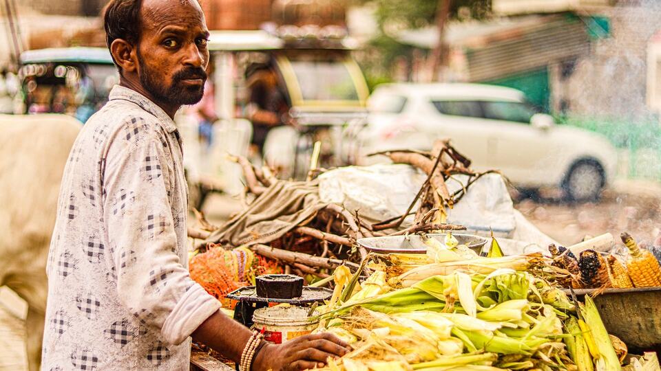 Street vendor grilling corn on the cob at a roadside stall in India