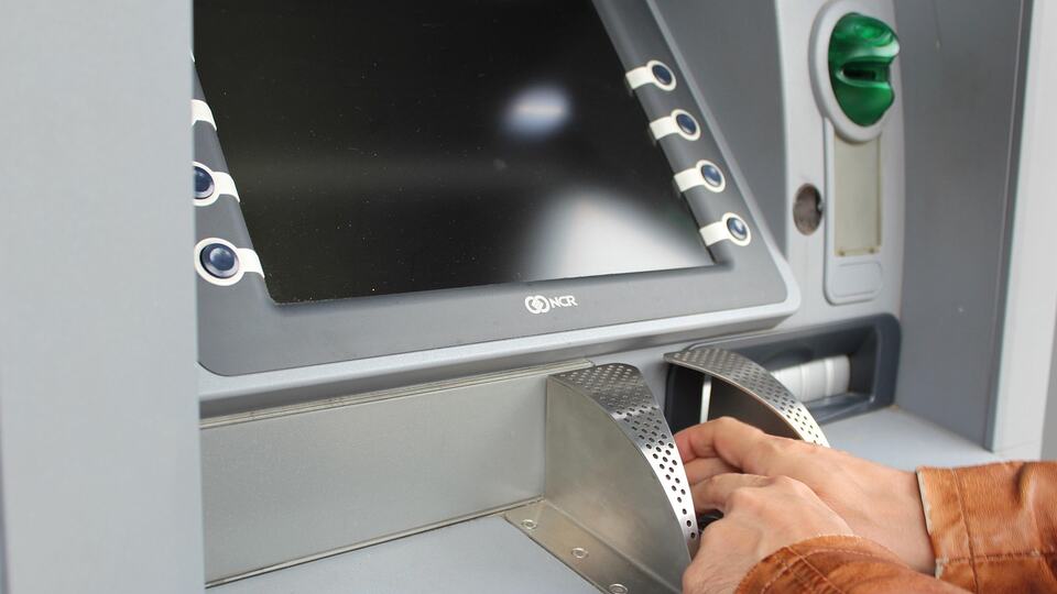 Hand entering a PIN at a cash machine