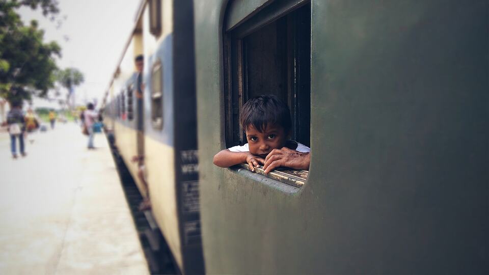 Child looking out of the window of a train at an Indian railway station