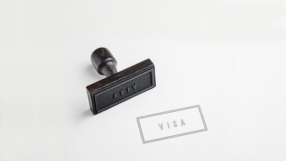 Visa stamp and rubber stamp on a passport page