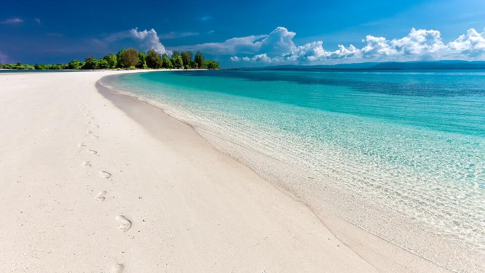 Footprints on a quiet white-sand beach with turquoise water