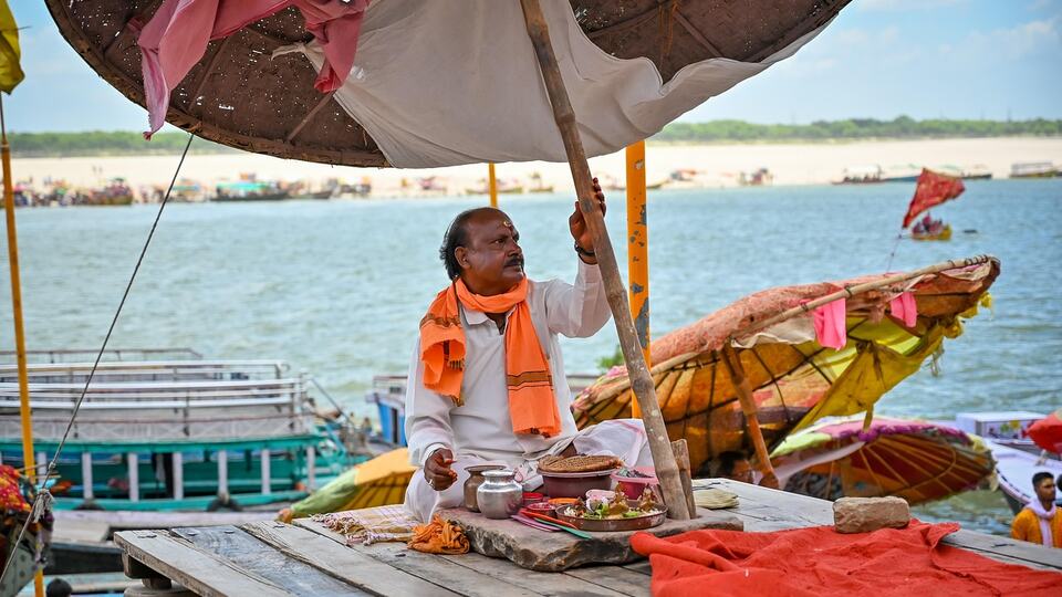 Hindu priest sitting under a parasol on the bank of the Ganges in Varanasi