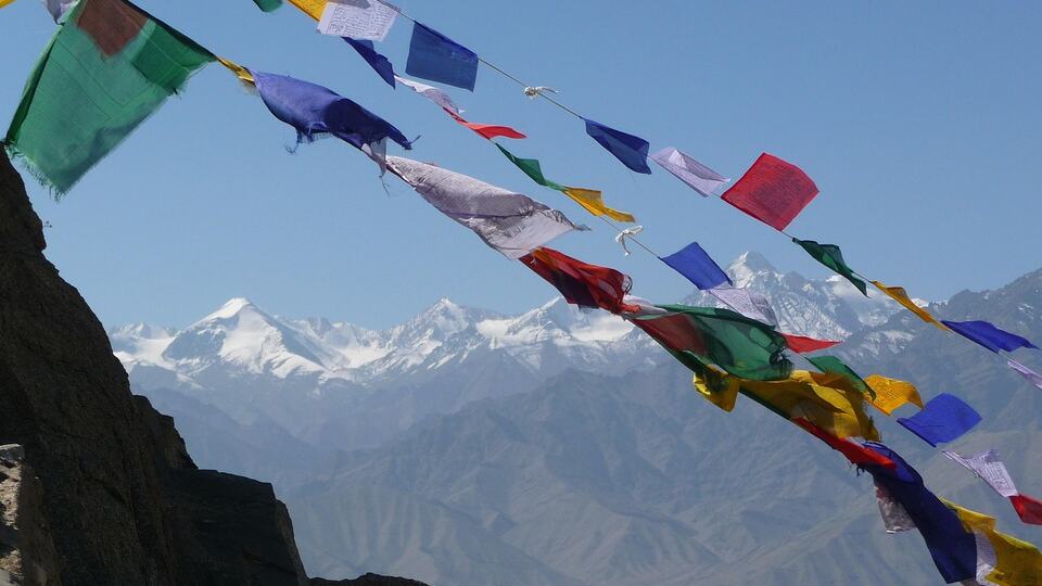 Buddhist prayer flags fluttering in front of snow-capped Himalayan peaks