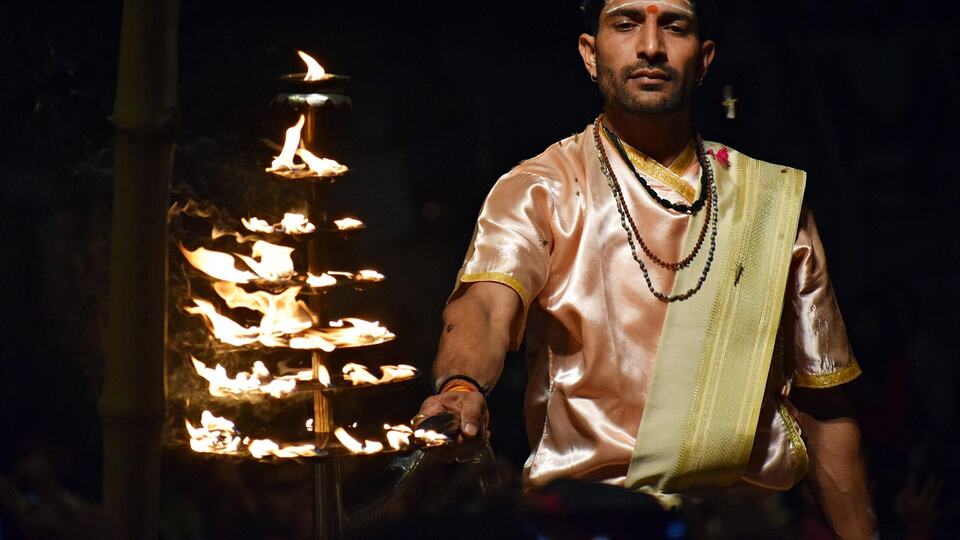 Priest holding a tiered fire lamp during the evening Ganga Aarti ceremony
